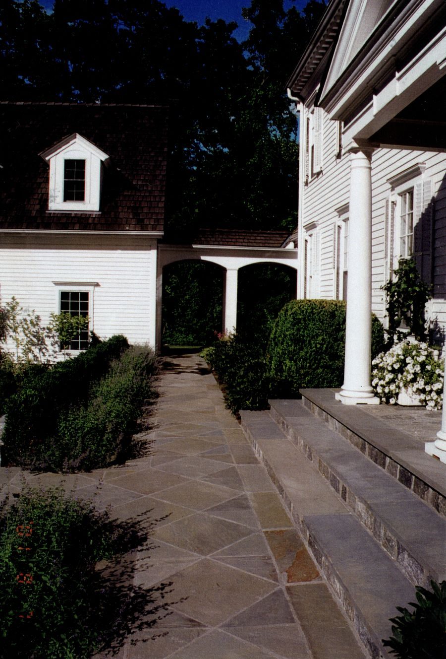 Flagstone walkway with stone steps alongside colonial home
