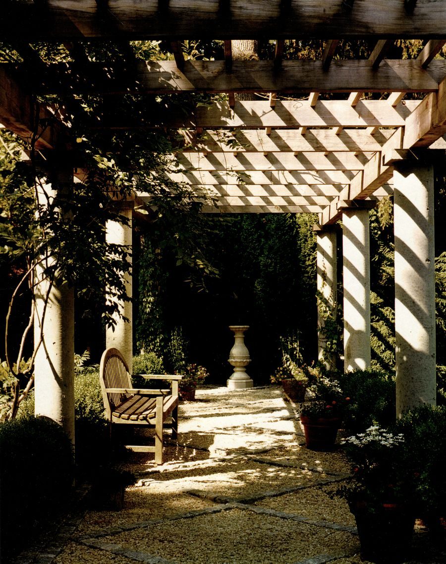 Stone pergola with garden bench and dappled light